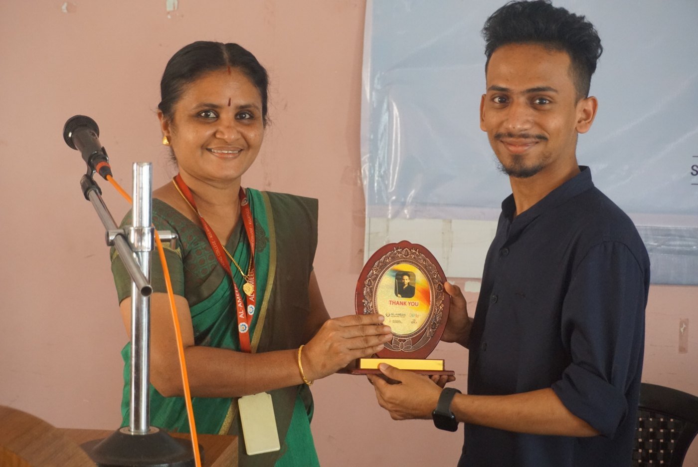Ajmal Basheer smiling as he receives a Thank You memento plaque from a faculty member at Al-Ameen Engineering College