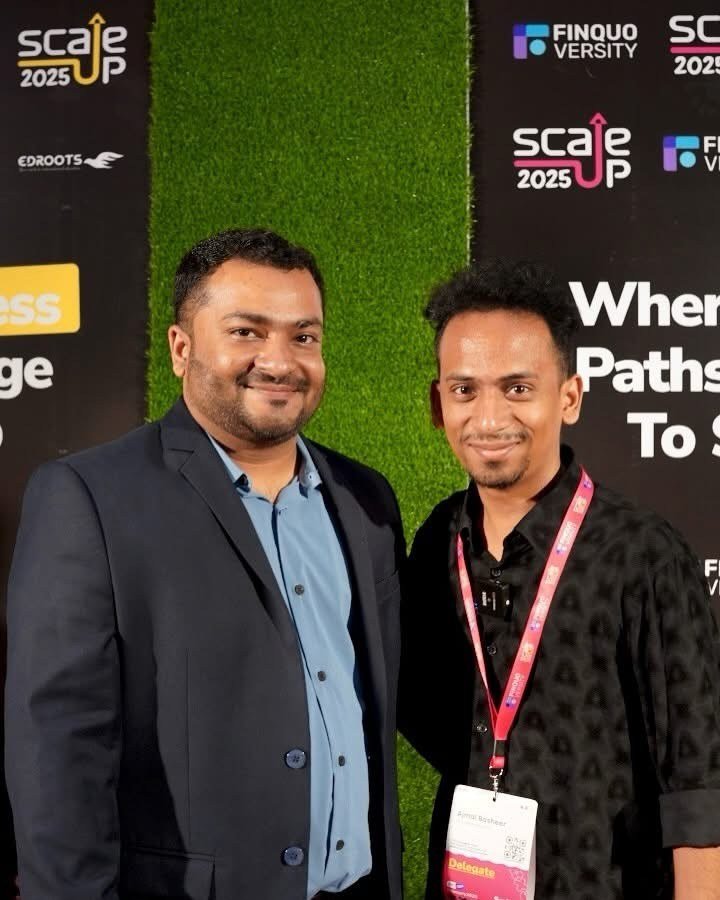 Ajmal Basheer, wearing a delegate lanyard, with a guest in front of the Scaleup 2025 backdrop