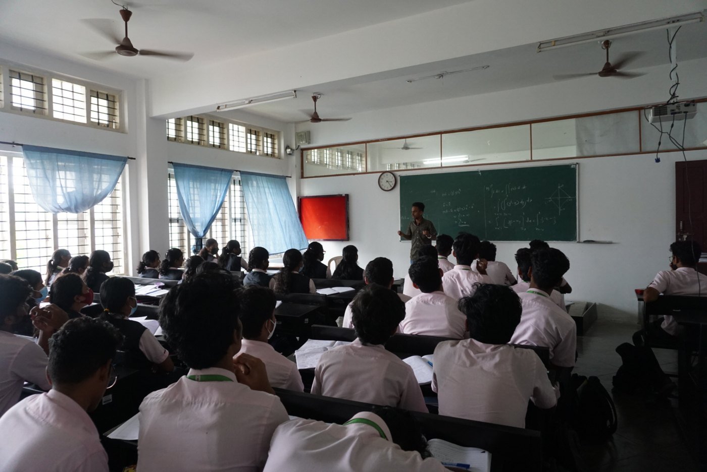 Ajmal Basheer teaching a full college classroom from the front, beside a chalkboard, as part of a Jobified training session