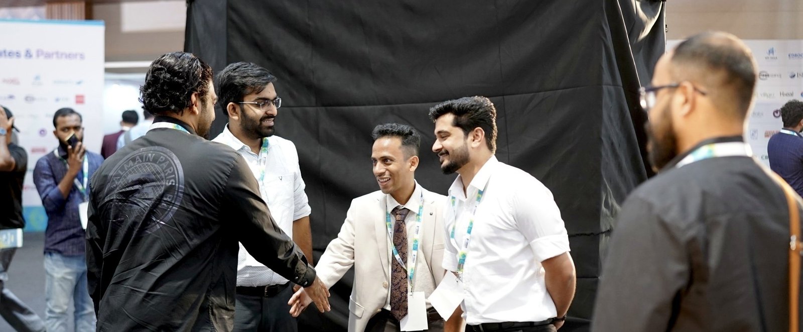 Ajmal Basheer in a beige suit shaking hands and talking with other founders at Money Conclave 2024
