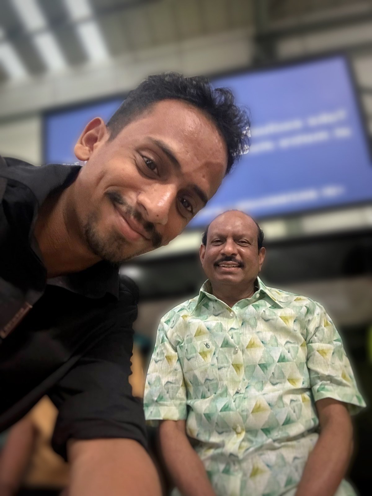 Ajmal Basheer taking a smiling selfie with M. A. Yusuff Ali, Chairman of Lulu Group, seated behind him